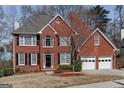 Inviting two-story red brick home with a well-manicured front yard and attached two-car garage at 2032 Stonewick Ct, Lawrenceville, GA 30043