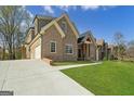 Side view of brick home with attached garage and concrete driveway on a sunny day at 5265 Brookhollow Dr, Douglasville, GA 30135