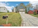 View of home with two-car garage and front lawn, with mail box at street and mature trees at 909 Chapman Cir, Stone Mountain, GA 30088