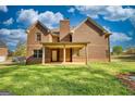 Brick home's rear exterior featuring a covered patio and lush green lawn at 117 Berkeley Way, Hampton, GA 30228
