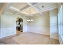 Elegant dining room with coffered ceilings, wainscoting, and an arched doorway to the kitchen at 117 Berkeley Way, Hampton, GA 30228