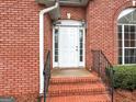 Close-up view of the brick home's front entrance with white door, sidelights, and iron railings at 205 Wynnfield Way, Mcdonough, GA 30252
