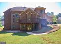 View of the multi-level deck and stone staircase leading up to the brick home and lush, green backyard at 65 Lotus Ln, Covington, GA 30016