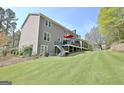 Expansive backyard featuring a deck, covered patio, lush lawn, and mature trees at 100 Smokerise Trce, Peachtree City, GA 30269