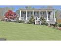 Charming two-story house featuring a columned porch and landscaped front yard on a sunny day at 100 Smokerise Trce, Peachtree City, GA 30269