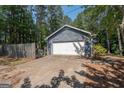 Detached garage with white door situated beside a wooden fence with a concrete driveway at 204 Mitchell Rd, Fayetteville, GA 30214