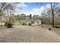 Exterior view of a home with gravel drive, detached garage, and partially wooded lot at 12435 Hamilton Rd # 536/- Ac, Chattahoochee Hills, GA 30268