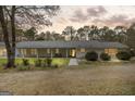 Exterior shot of a ranch-style home with a covered porch, showcasing a warm ambiance at twilight at 12435 Hamilton Rd # 536/- Ac, Chattahoochee Hills, GA 30268