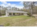 Rear exterior showing covered porch, spacious yard, and mature trees at 12435 Hamilton Rd # 536/- Ac, Chattahoochee Hills, GA 30268