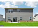 Backyard view of gray vinyl siding and sliding glass door to a level lawn with partial brick foundation at 864 Maduro Way, Mcdonough, GA 30253
