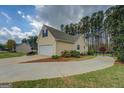 Side exterior view showing two-car garage, long driveway, and manicured landscaping at 116 Laurel Ln, Social Circle, GA 30025