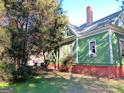 Two-story home with green siding and a brick foundation, surrounded by mature trees at 109 Smith St, Locust Grove, GA 30248