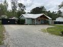 Exterior view of charming house with a metal roof, wood beam porch, and gravel driveway at 6121 N Main Se St, Acworth, GA 30101