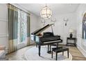 Elegant living room featuring a grand piano, large windows, and custom wall paneling at 140 Newhaven Dr, Fayetteville, GA 30215