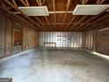 View of the garage interior featuring a concrete floor, exposed rafters, and lighting at 1397 Iron Gate Blvd, Jonesboro, GA 30238