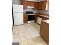 Functional kitchen with wood cabinets, white appliances, and tile flooring at 5575 Marbut Rd, Lithonia, GA 30058