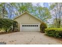 Attached two-car garage with white door and siding, surrounded by mature landscaping at 115 Bob White Trl, Fayetteville, GA 30215