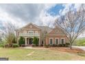 Elegant brick home featuring a covered balcony, manicured shrubs, and a lush green lawn at 217 Brunswick Dr, Tyrone, GA 30290