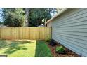 View of backyard with a brand new wooden fence, manicured lawn, and exterior of home with green siding at 1475 Woodington Cir, Lawrenceville, GA 30044