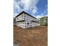 The house is under construction; house wrap is visible on the two story home with bare red clay property and lumber debris at 523 Courthouse Park Dr, Temple, GA 30179