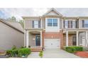 Inviting townhome featuring a garage, brick detailing, and lush, green landscaping at 2705 Maple Park Pl # 29, Cumming, GA 30041