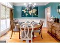 Stylish dining room features hardwood floors, a round wooden table, and a teal accent wall with unique world map art at 101 Westminster Way, Mcdonough, GA 30253