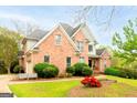 A charming brick house featuring a well-maintained lawn, lush bushes, and a cozy driveway leading to an attached garage at 101 Westminster Way, Mcdonough, GA 30253