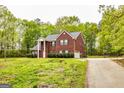 Brick home surrounded by a grassy lawn and mature trees, featuring dark shutters and an attached garage at 1015 Middlebrook Dr, Mcdonough, GA 30252