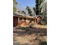 Exterior shot of a single-story brick home surrounded by mature trees and landscaping at 8395 Rivertown Rd, Fairburn, GA 30213