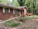 Exterior of brick home with a red accent and blooming azaleas in a natural landscape at 8395 Rivertown Rd, Fairburn, GA 30213