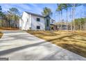Modern farmhouse with a concrete driveway, white siding, black windows, and a spacious lawn at 140 Wesley Pl, Fayetteville, GA 30214