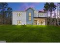 Modern farmhouse with white siding, a gray accent, black windows, and a lush green lawn at dusk at 140 Wesley Pl, Fayetteville, GA 30214