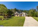 Traditional single-Gathering home with a landscaped front yard, mature trees, and a curved driveway at 230 Hidden Brook Trl, Fayetteville, GA 30215