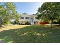 Inviting yellow house with a large, well-maintained front yard and shade trees in a sunny day at 3540 Owl Brow Ct, Cumming, GA 30028
