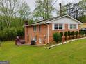 Rear view of brick home with lush lawn and stairway to elevated deck at 6501 River Run Rd, Riverdale, GA 30274