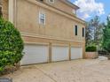 Three-car garage featuring white doors and ample parking space, adjacent to a landscaped area at 5297 Heron Bay Blvd, Locust Grove, GA 30248