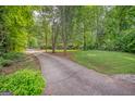 View of a long driveway leading to a brick home surrounded by lush landscaping at 205 Olde Oak Dr, Jonesboro, GA 30238