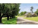 Charming single-story home with a long driveway, green lawn, and mature trees providing ample shade at 321 Harris Ave, Locust Grove, GA 30248
