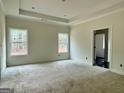 Bright primary bedroom featuring large windows, plush carpeting and a tray ceiling at 4585 Parkwood Rd, Social Circle, GA 30025