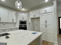 Elegant kitchen showcases sleek white cabinetry, stainless steel appliances, and a stylish island with marble countertops at 4601 Parkwood Rd, Social Circle, GA 30025