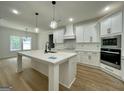 A modern kitchen features white cabinets, stainless appliances, and a spacious center island with quartz countertops at 4601 Parkwood Rd, Social Circle, GA 30025