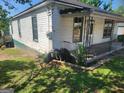 Cozy house with a covered porch surrounded by green yard and trees, creating a serene, vintage setting at 34 Pine St, Porterdale, GA 30014
