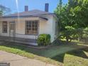 Charming single-story home with a covered porch, surrounded by a green lawn and trees for added privacy at 34 Pine St, Porterdale, GA 30014