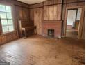 View of the living room with a fireplace, original wood floors, and piano at 34 Pine St, Porterdale, GA 30014