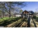 Rear exterior view of a house with a deck, lush greenery, and mature trees at 689 Hardin Rd, Temple, GA 30179