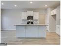 Open kitchen with a large island, stainless steel appliances, and wooden flooring at 300 San Anselmo St, Locust Grove, GA 30248
