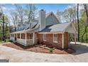 A beautiful home showing a brick and stone exterior, a covered patio, and mature trees at 9055 Carroll Manor Dr, Sandy Springs, GA 30350