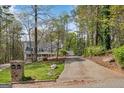 Exterior shot of home with a long driveway and surrounding mature trees at 9055 Carroll Manor Dr, Sandy Springs, GA 30350
