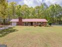 Charming ranch-style home with a red metal roof, brick chimney and an expansive green lawn at 361 Cecil Hunter Rd, Moreland, GA 30259