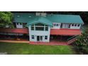 Aerial view showcases a home with a green metal roof, surrounding deck, and a well-maintained lawn at 2316 Emerald Dr, Jonesboro, GA 30236